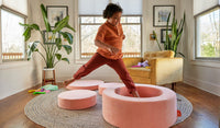 A child leaps into the hoop of a Blossom light pink Chunk play ottoman, set up as stepping stones.