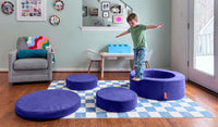 A child balances on the pieces of a Chunk play ottoman in Nebula vibrant indigo, set up as stepping stones.