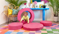 A child climbs through the hoop of a hot pink Popstar Chunk play ottoman.