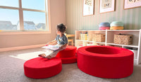 A child reads a book while seated on the pieces of a Trolley red Chunk play ottoman.