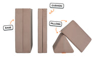 Four pieces of a earthy taupe Nugget play couch lined up one foldable base one foldable cushion and two triangular pillows.