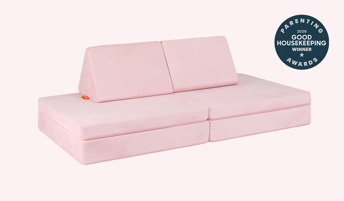 A Heartthrob blush pink Nugget play couch set up in a kids' sofa configuration.