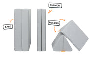 Four pieces of a light gray Nugget play couch lined up: one foldable base, one foldable cushion, and two triangular pillows.