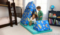 Two children play on the pieces of a vibrant Ms. Rachel-patterned Nugget play couch, set up as a tent and hurdle.