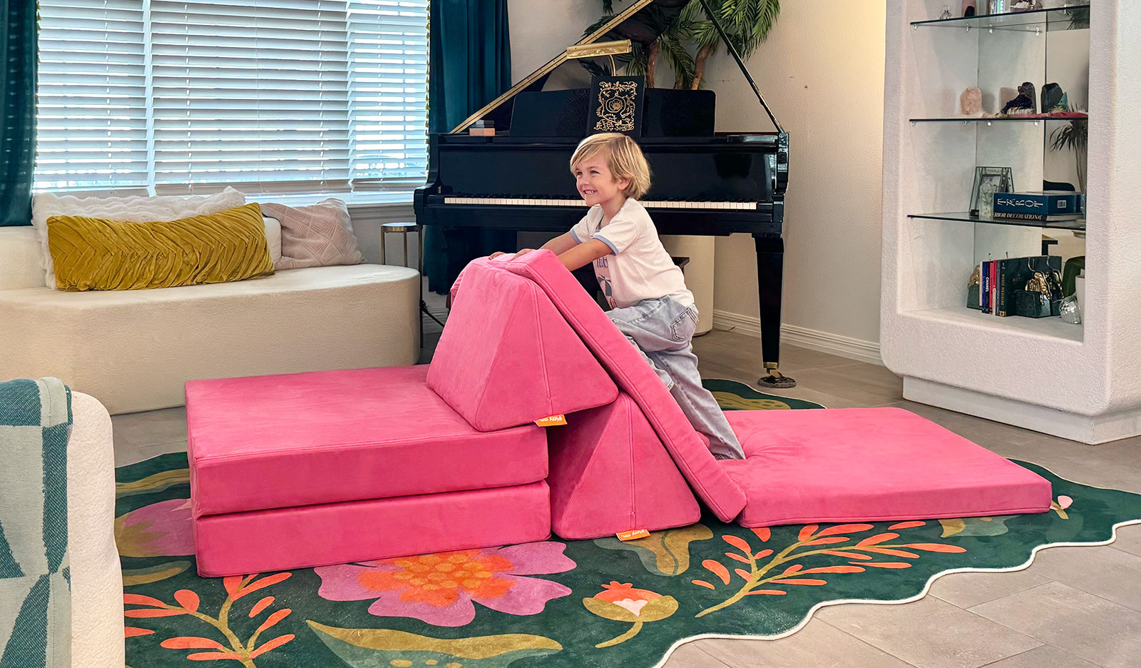 A child climbs the pieces of a hot pink Popstar Nugget play couch.