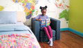 A child reads a book in a bedroom while seated on a denim blue Smore play chair.