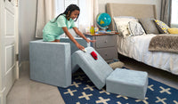A child races toy cars down the pieces of a light gray-blue Smore play chair.