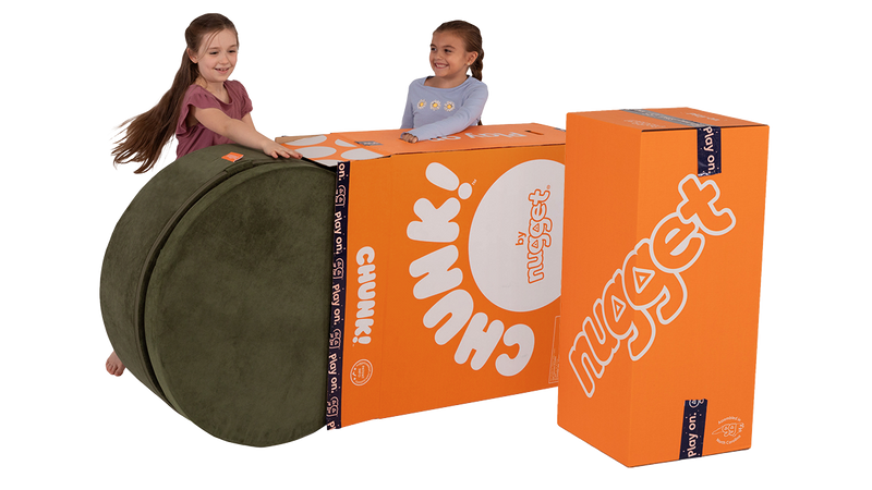 Two children unbox Nugget play furniture, starting by rolling a Chunk play ottoman out of a Big Orange Box.