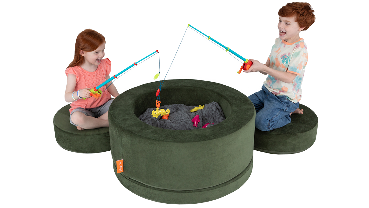 Two children play a magnetic fishing pole game inside a forest green play storage ottoman, using the pieces as seats.