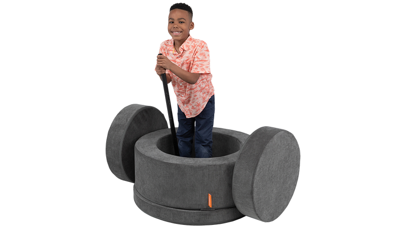 A child plays inside a dark gray foam ottoman, enjoying imaginative, open-ended play.
