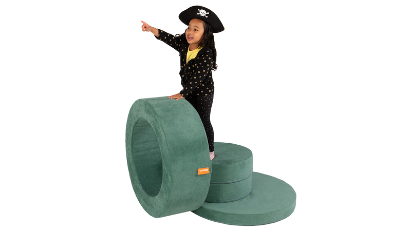 A child plays and pretends to helm the bridge of a pirate ship, built from one sea-green Chunk storage ottoman.