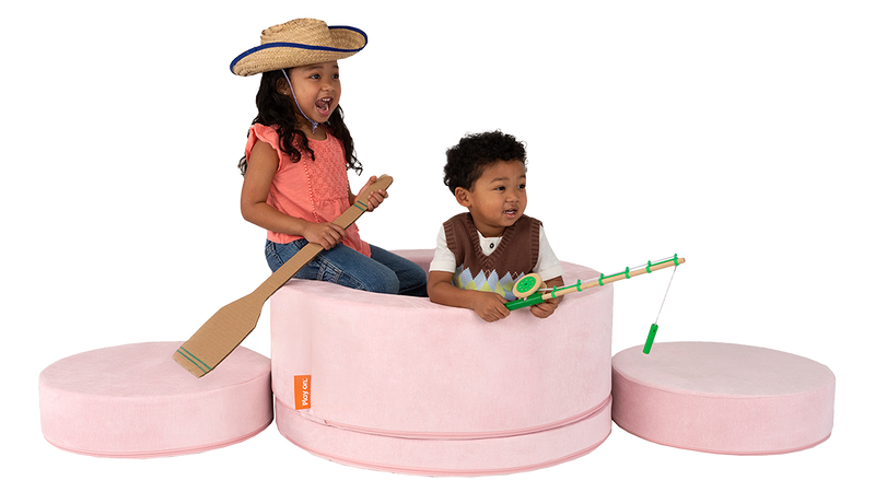 Two children play and pretend they’re on a fishing boat, built from one light-pink Chunk storage ottoman.