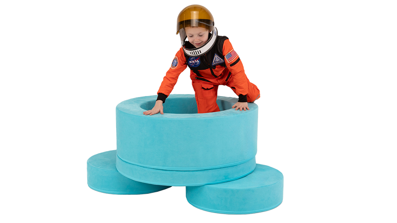 A child jumps into the hoop of a turquoise Chunk storage ottoman, playing and pretending to be an astronaut.