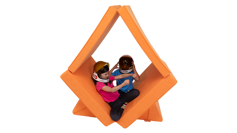 Two children in space helmets pretend to steer a spaceship built from one orange Nugget play couch.