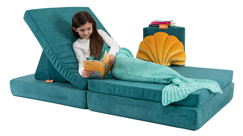 A child reclines and reads a book on a one-Nugget lounge build — created with one teal Nugget play couch.