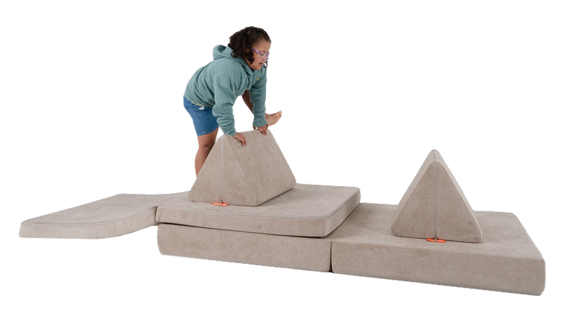A child plays on an obstacle course made from one light beige Nugget play couch.
