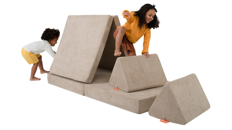 Two children play on an obstacle course made from one beige Nugget play couch.