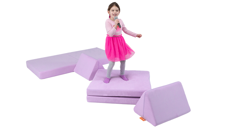 A child sings into a microphone and dances on a one-Nugget stage build, made from a light purple Nugget play couch.