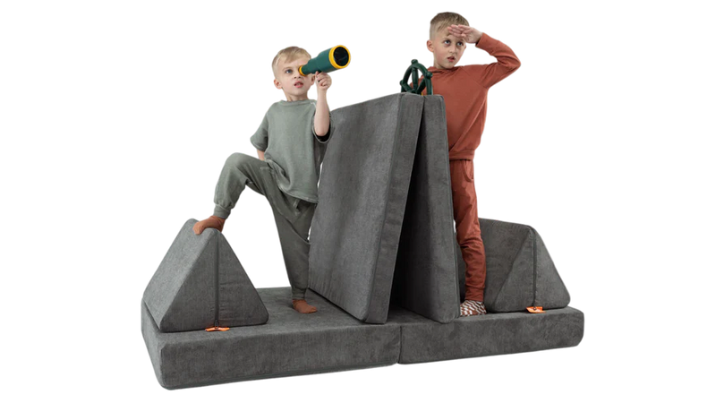 Two children eye the horizon from their one-Nugget boat build, made from a charcoal gray Nugget play couch.