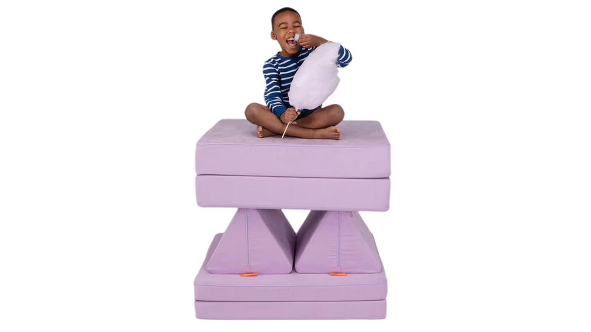 A child eats light purple cotton candy from his tower build — created using one light purple Nugget play couch.