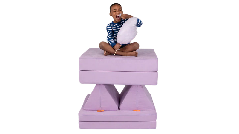 A child eats light purple cotton candy from his tower build — created using one light purple Nugget play couch.