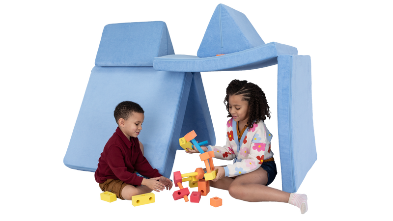 Two children play with blocks under a one-Nugget fort build, made from a baby blue Nugget play couch.