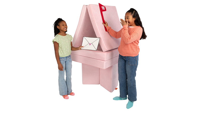 Two children pretend to send letters in their one-Nugget mailbox build, made from a light pink Nugget play couch.