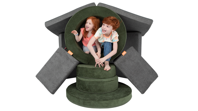 Two kids play around a pretend portal built from Nugget play furniture — one Nugget play couch and one Chunk play ottoman.