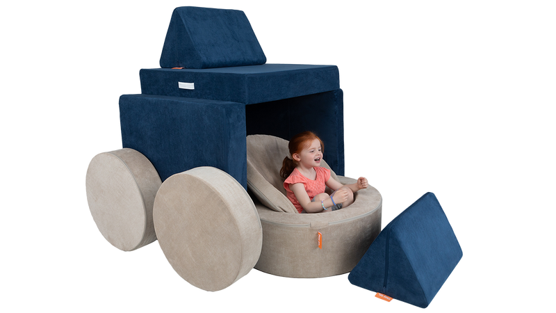 A child engages her imagination to pretend a Nugget play couch and Chunk play ottoman are a large semi-truck.