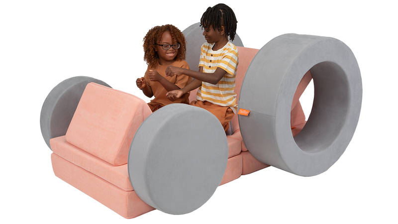 Two kids engage in imaginative, open-ended play in a modular foam furniture car made with one Nugget and one Chunk ottoman.