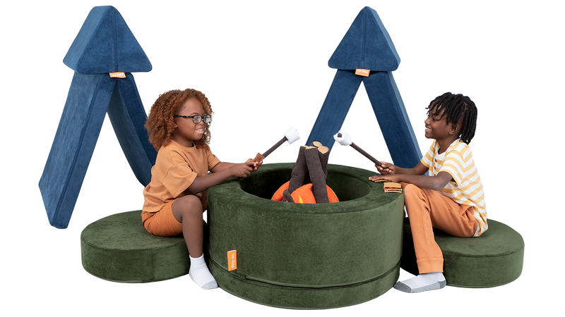 Two children play at a pretend campsite, with tents made out of a Nugget play couch, and a campfire made from a Chunk.
