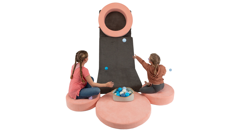 Two kids play a Nuggety version of Skee-ball, using one Nugget play couch as the ramp and a Chunk play ottoman as the target.