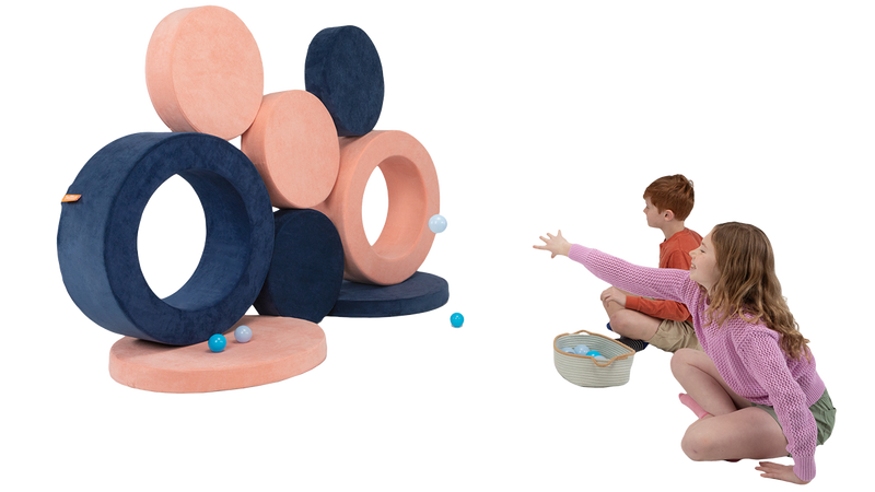 Two children toss small balls at a wall of targets made with the pieces of two Chunk play ottomans.
