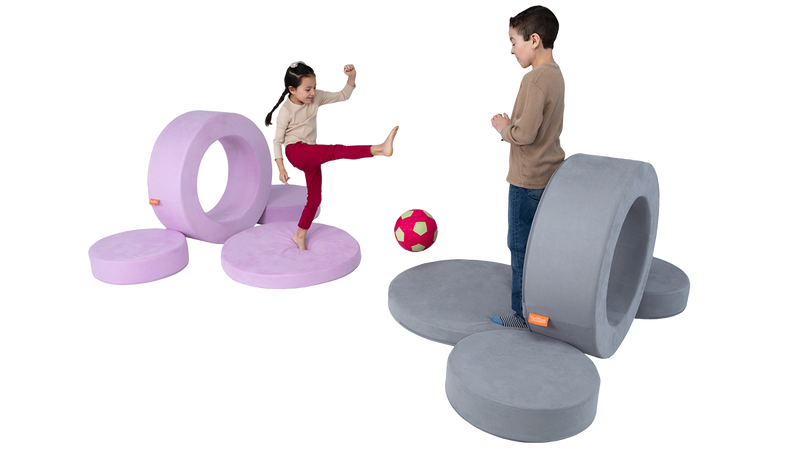 Two children take aim at opposite targets with a soft soccer ball, built using the Chunk play ottoman hoops.