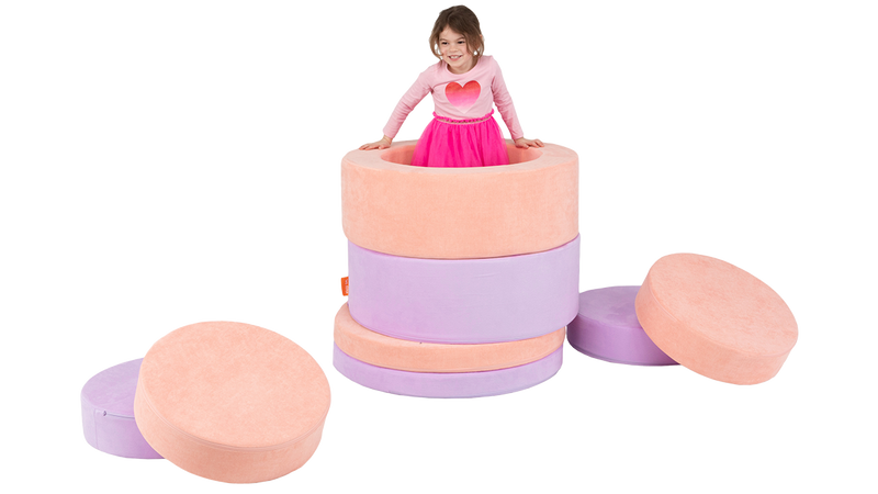 A child pops out of a tower constructed with the pieces of two Chunk play ottomans.