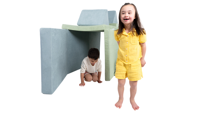 Two children play inside a tunnel build, made with two Nugget play couches.