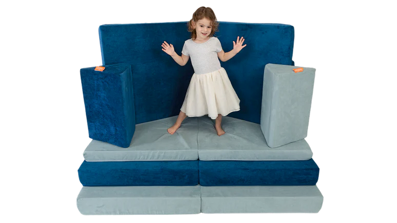 A child dances on top of a stage build, constructed using two Nugget play couches.