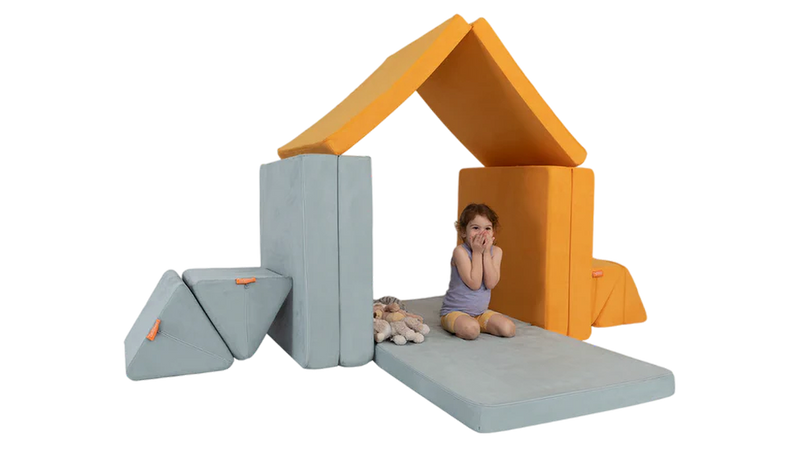 A child plays with her stuffed animals inside a house build, constructed using two Nugget play couches.