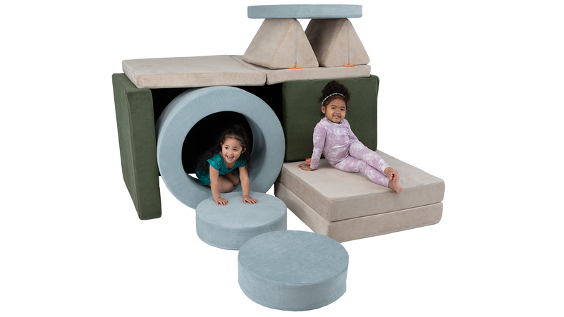 Two children crawl around and on top of a fort built from two Nugget play couches and one Chunk play ottoman.