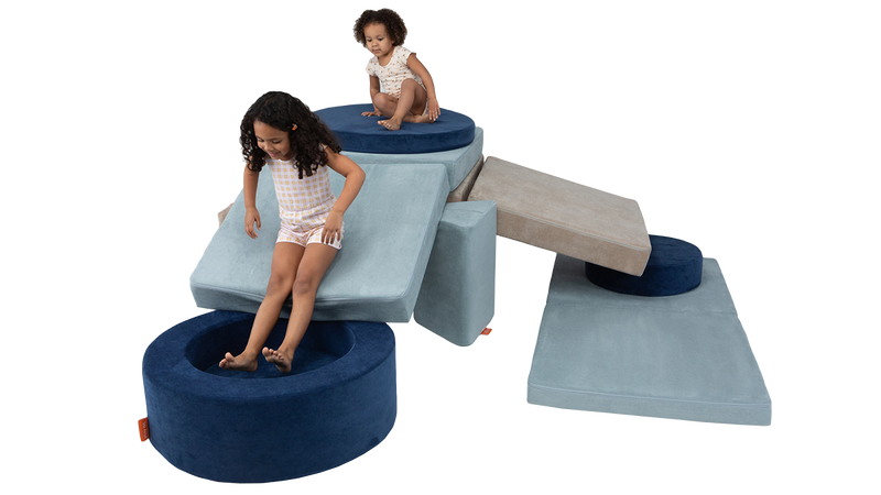 Two children play on an obstacle course made from two Nugget play couches and one Chunk play ottoman.