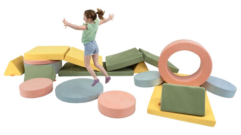 A kid leaps from one piece of play furniture to the next, exploring an obstacle course made from two Nuggets & two Chunks.