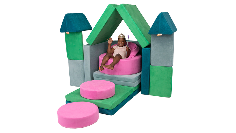 A child sits upon a Nuggety throne, built from three Nugget play couches and one Chunk play ottoman.