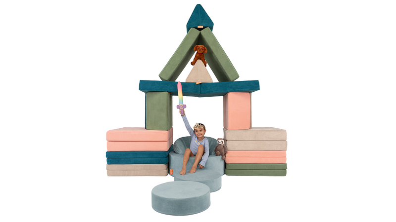 A child sits triumphant on a Chunk play ottoman throne under a four-Nugget castle trellis.