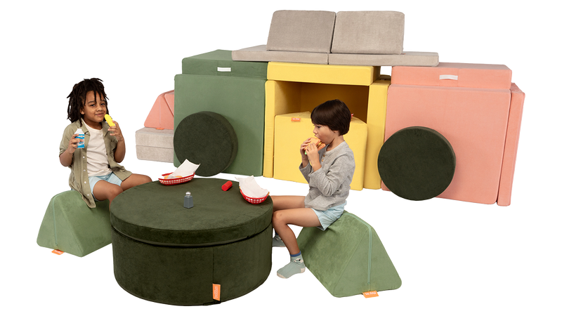 Two children play in an imaginative pretend diner, made from Nugget play furniture — two play ottomans and four play couches.