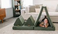 A child laughs and poses on his belly inside a tented piece of a Willow forest green play couch by Nugget.