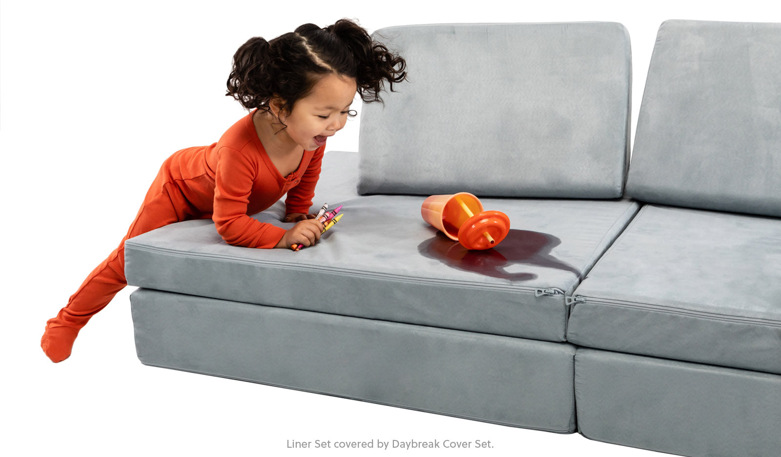 Little girl spilling her juice on the Nugget® Koala couch