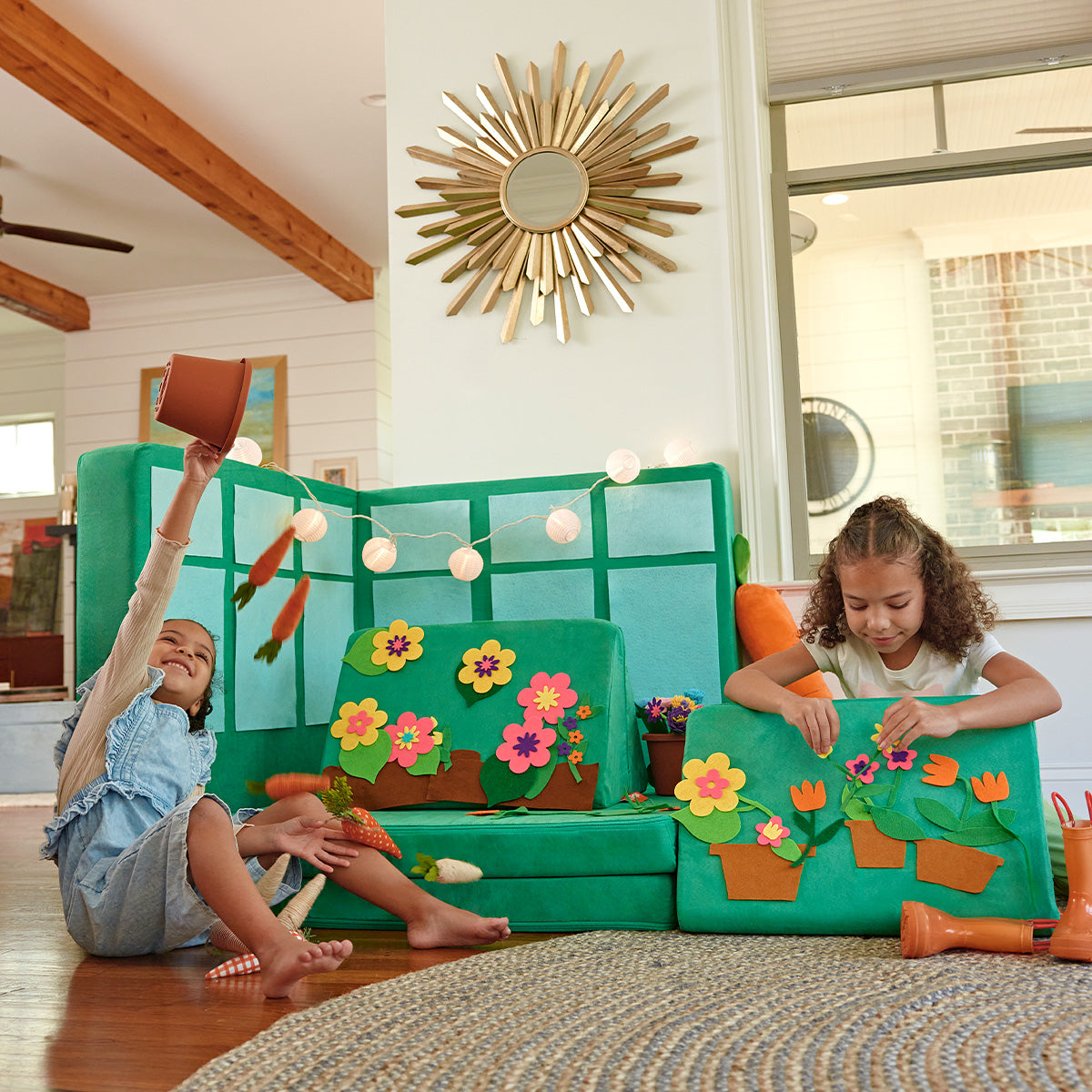 Two kids pretend to garden in a greenhouse made from a bright green Nugget play couch and felt flowers.