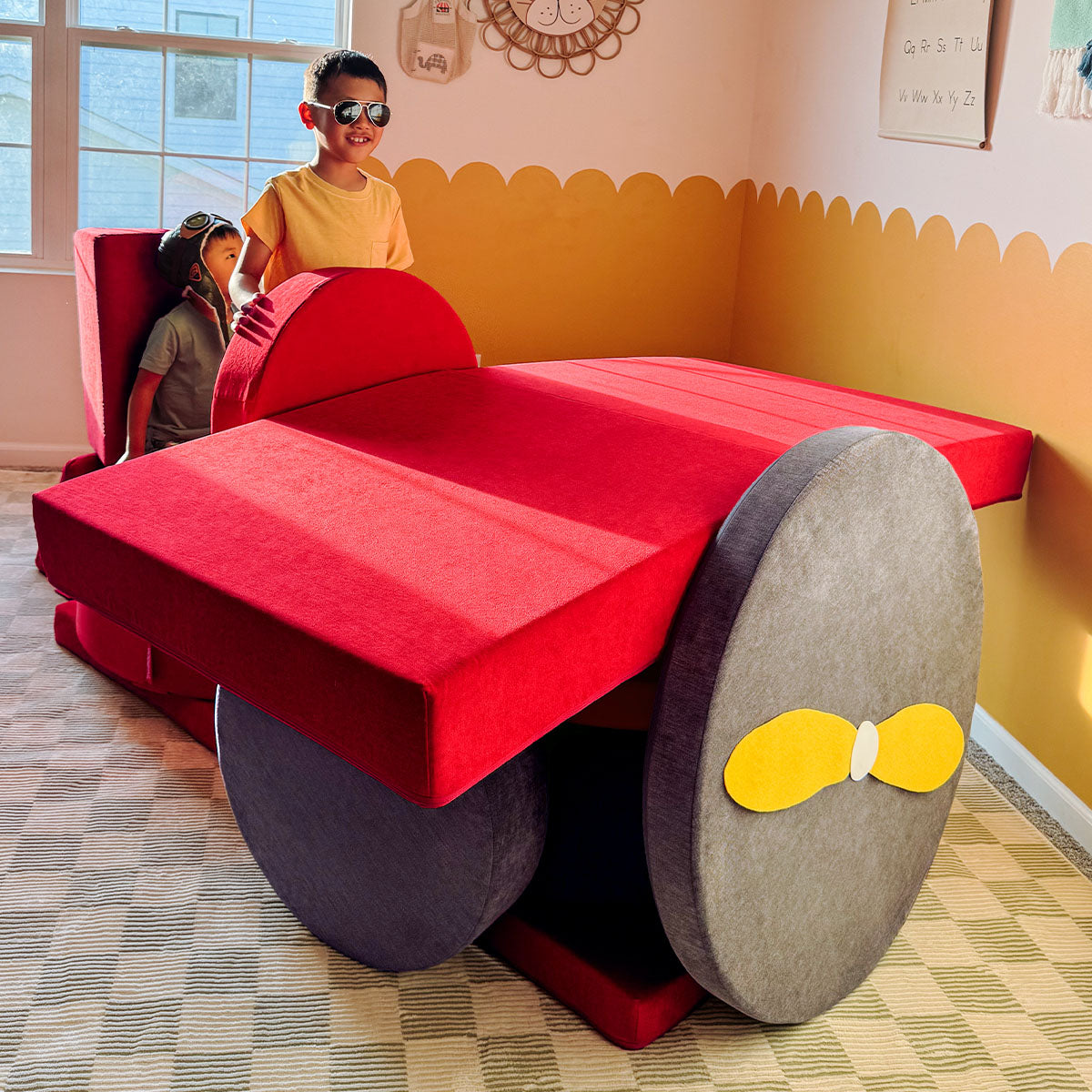 A child throws play leaves in the air alongside a Chunk play ottoman arranged as a cornucopia.