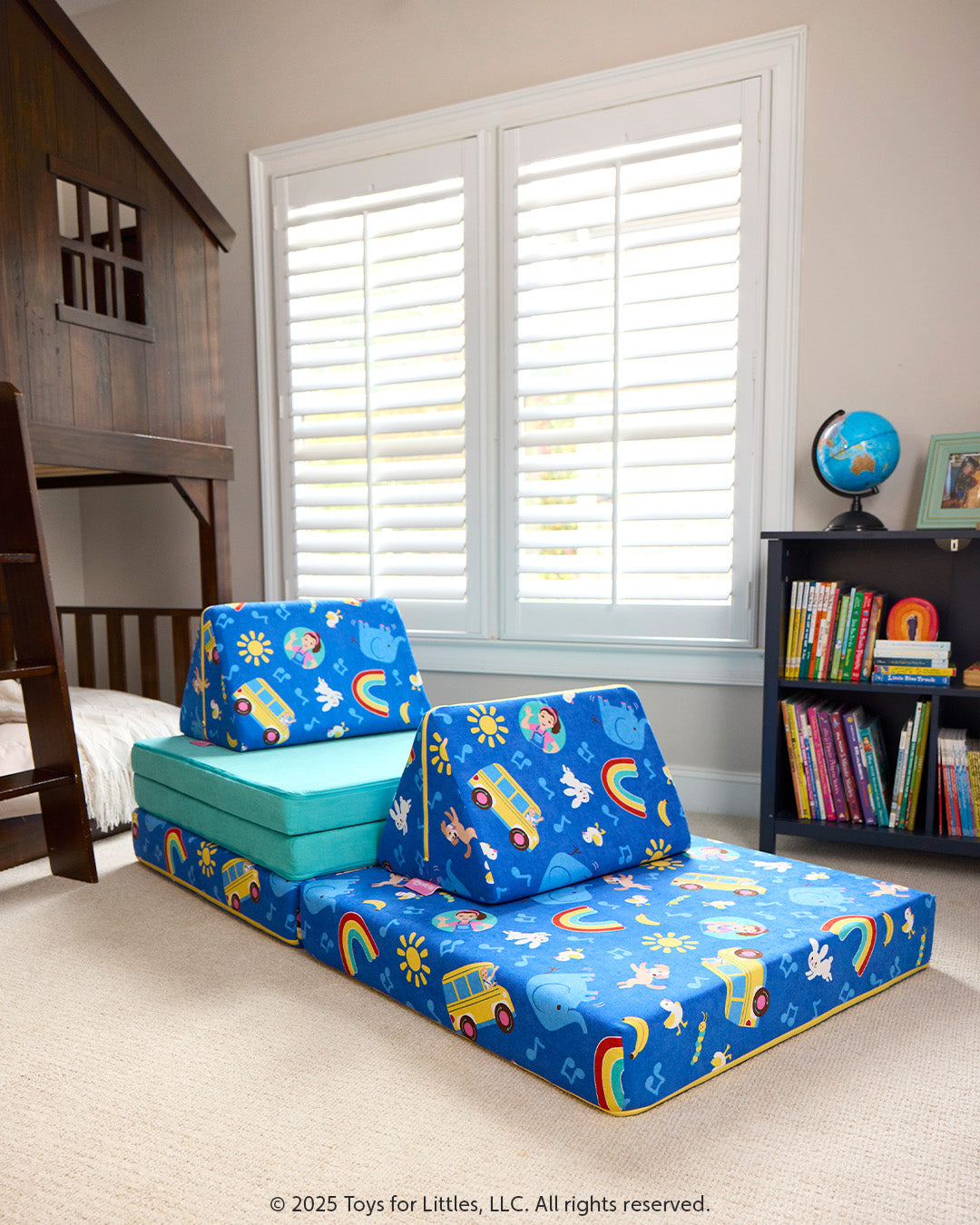 A colorful Ms. Rachel Nugget play couch is shown, featuring blue fabric with a pattern of icons from popular Ms. Rachel songs.