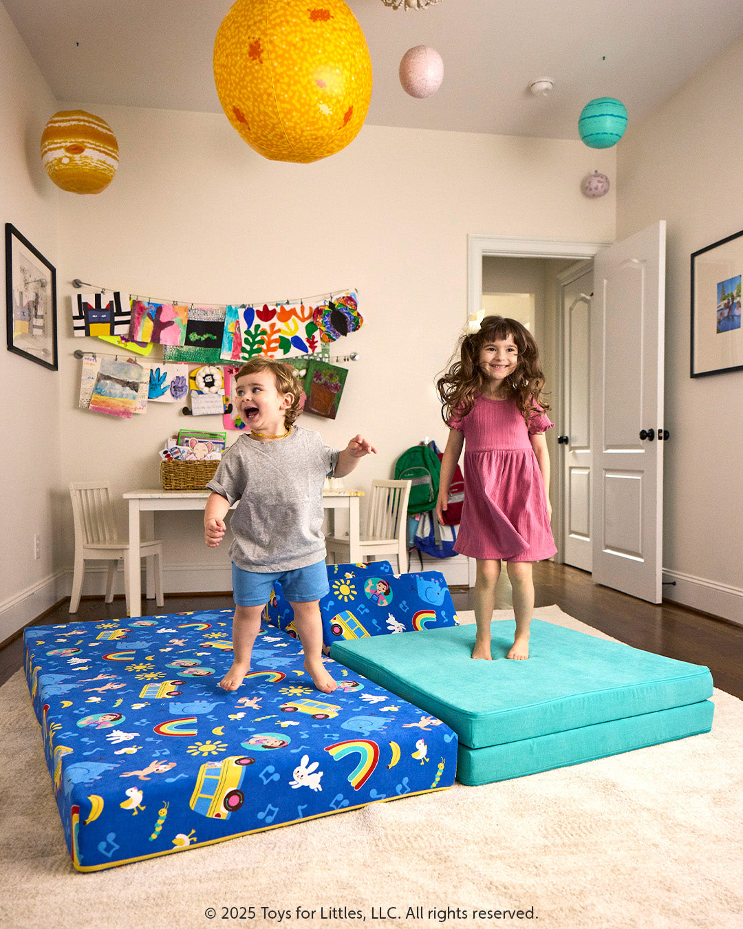 Two children smile and jump on the pieces of a colorful Ms. Rachel Nugget, patterned with icons from popular Ms. Rachel songs.